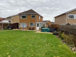back garden with extensive lawn with modern home in the background