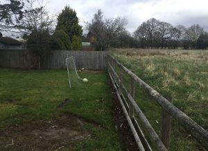 post and rail fence with pasture to the right of it and back garden with goal post to the left